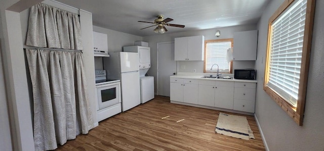 156 W 9th Ave, Colville, WA 99114 - kitchen featuring white appliances, estacked washer and dryer, under cabinet range hood, a sink, and light wood-type flooring