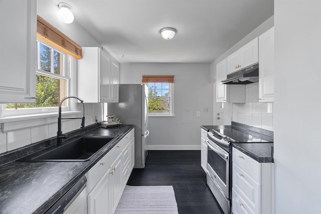 2417 W Euclid Ave, Spokane, WA 99205 - kitchen featuring under cabinet range hood, appliances with stainless steel finishes, dark countertops, a sink, and baseboards