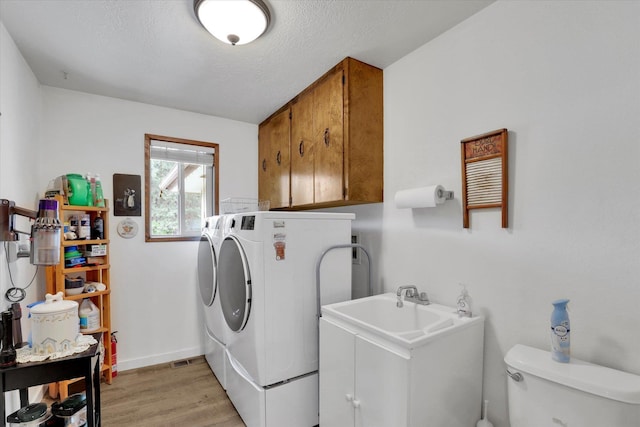 4921 W Londale Ct, Spokane, WA 99208 - washroom featuring washing machine and clothes dryer, light wood finished floors, a textured ceiling, baseboards, and cabinet space
