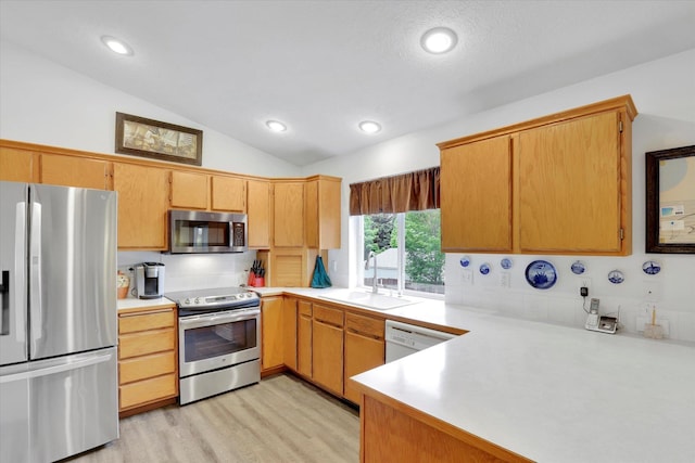 15711 N Unicorn Ct, Mead, WA 99021 - kitchen with appliances with stainless steel finishes, light countertops, vaulted ceiling, light wood-style flooring, and a peninsula