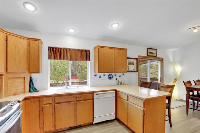 15711 N Unicorn Ct, Mead, WA 99021 - kitchen with white dishwasher, a peninsula, stainless steel electric range, light wood-type flooring, and light countertops