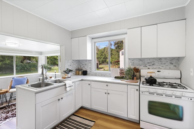 2526 E 8th Ave, Spokane, WA 99202 - kitchen with white gas stove, a sink, decorative backsplash, white cabinets, and light countertops