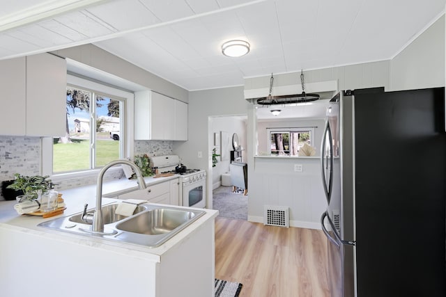 2526 E 8th Ave, Spokane, WA 99202 - kitchen featuring freestanding refrigerator, white gas range oven, white cabinets, a sink, and backsplash