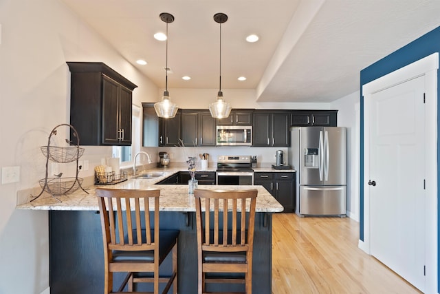 18218 E Michielli Ave, Spokane Valley, WA 99016 - kitchen with stainless steel appliances, a sink, light wood-type flooring, a peninsula, and light stone counters