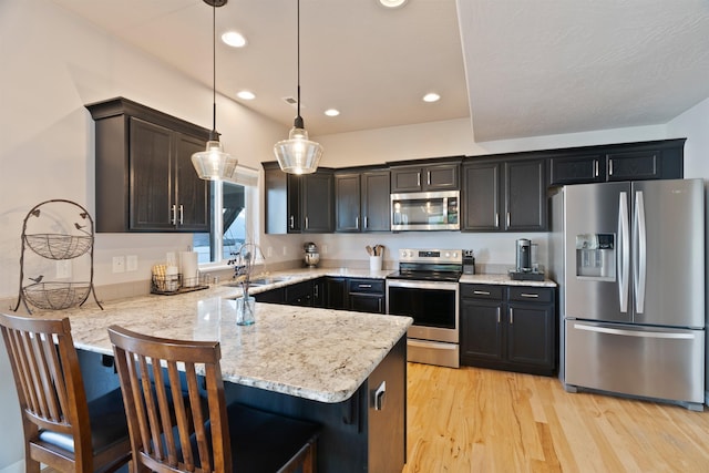 18218 E Michielli Ave, Spokane Valley, WA 99016 - kitchen with stainless steel appliances, a sink, a peninsula, light wood finished floors, and decorative light fixtures