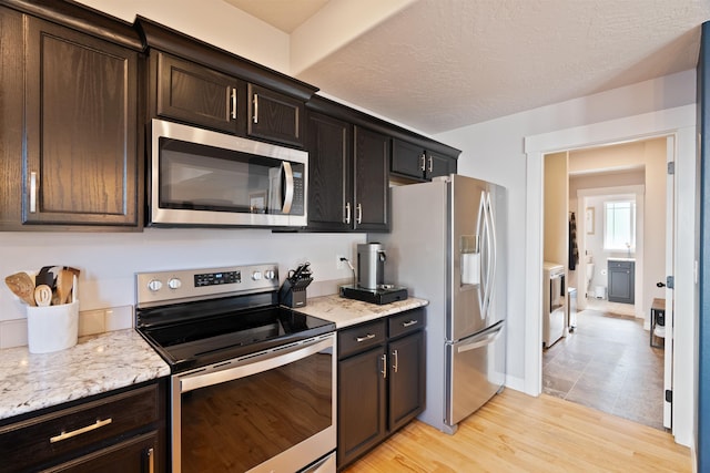 18218 E Michielli Ave, Spokane Valley, WA 99016 - kitchen featuring appliances with stainless steel finishes, washer / dryer, light stone countertops, light wood-style flooring, and baseboards
