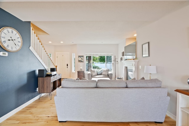 18218 E Michielli Ave, Spokane Valley, WA 99016 - living room featuring stairs, light wood-style flooring, baseboards, recessed lighting, and a glass covered fireplace