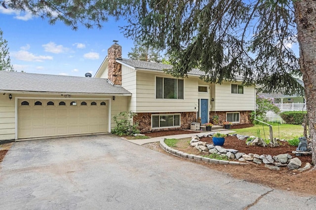 122 E Circle Dr, Newport, WA 99156 - bi-level home with asphalt driveway, a chimney, and an attached garage