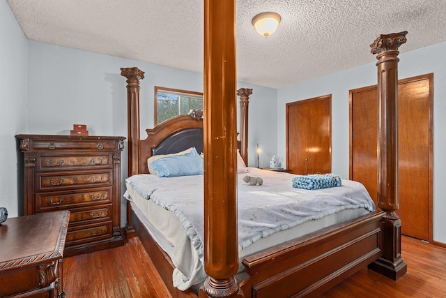 122 E Circle Dr, Newport, WA 99156 - bedroom with dark wood finished floors, ornate columns, a textured ceiling, and multiple closets
