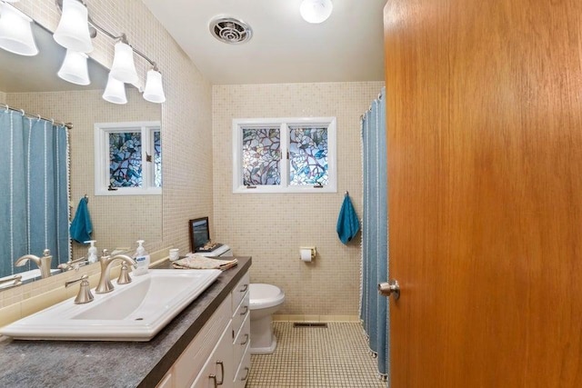 536 E 1st Ave, Colville, WA 99114 - full bathroom featuring vanity, tile patterned flooring, toilet, tile walls, and a shower with shower curtain