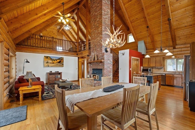3947 N Deer Lake Rd, Loon Lake, WA 99148 - dining area featuring high vaulted ceiling, wood ceiling with exposed beams, light wood-style floors, a fireplace, and a ceiling fan