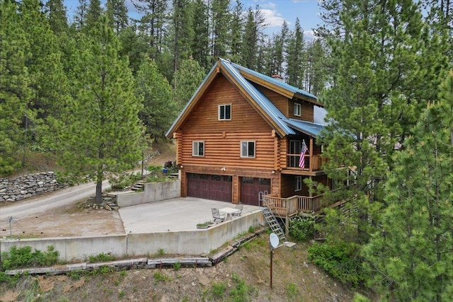 3947 N Deer Lake Rd, Loon Lake, WA 99148 - view of home's exterior featuring log exterior, an attached garage, concrete driveway, a balcony, and metal roof