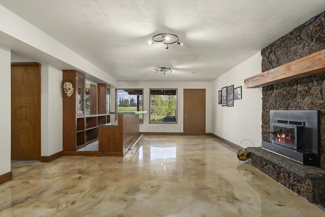 10409 E Palouse Hwy, Valleyford, WA 99036 - unfurnished living room featuring a textured ceiling, baseboards, finished concrete flooring, and a stone fireplace