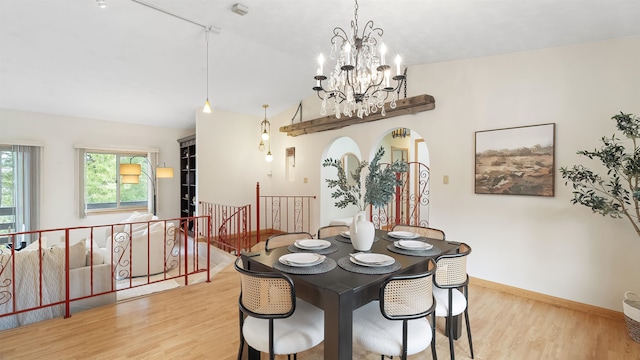 13110 W Charles Rd, Nine Mile Falls, WA 99026 - dining area featuring wood finished floors, a chandelier, baseboards, vaulted ceiling, and arched walkways
