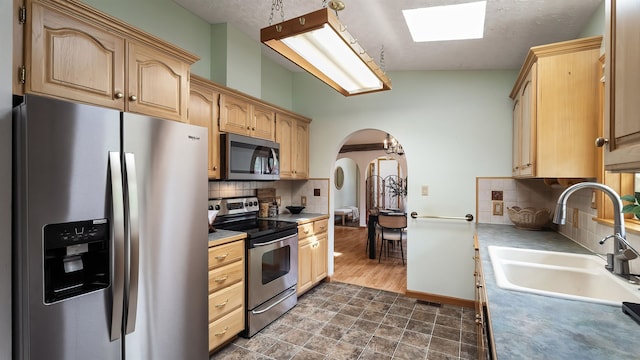 13110 W Charles Rd, Nine Mile Falls, WA 99026 - kitchen featuring stainless steel appliances, a sink, arched walkways, and light brown cabinets