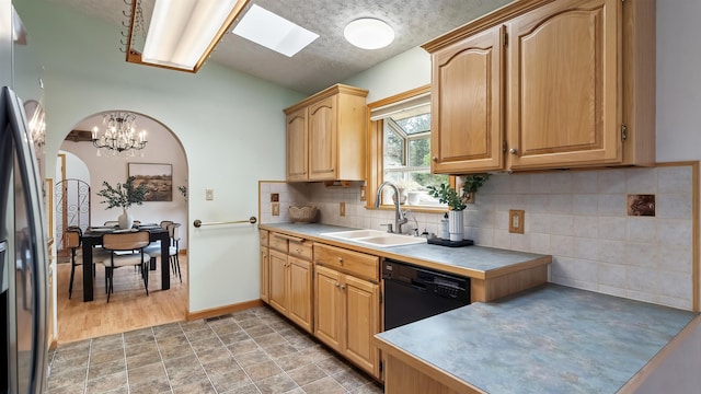 13110 W Charles Rd, Nine Mile Falls, WA 99026 - kitchen with a sink, black dishwasher, freestanding refrigerator, arched walkways, and a chandelier