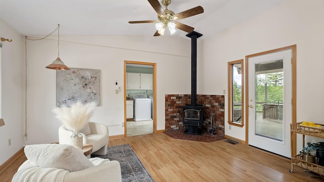 13110 W Charles Rd, Nine Mile Falls, WA 99026 - living room featuring washer / clothes dryer, a wood stove, lofted ceiling, light wood-type flooring, and ceiling fan