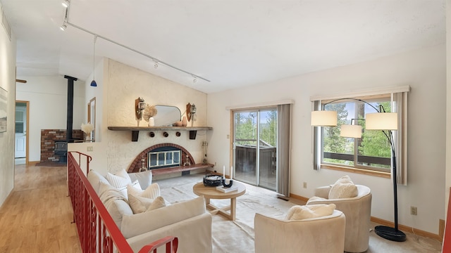 13110 W Charles Rd, Nine Mile Falls, WA 99026 - living area with rail lighting, light wood-type flooring, a wood stove, baseboards, and lofted ceiling