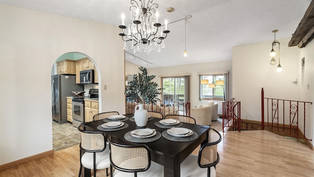 13110 W Charles Rd, Nine Mile Falls, WA 99026 - dining room with light wood-style floors, arched walkways, a chandelier, and baseboards