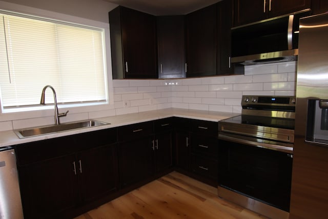 117 5th Ave, Cusick, WA 99119 - kitchen with appliances with stainless steel finishes, a sink, light wood-style floors, and tasteful backsplash