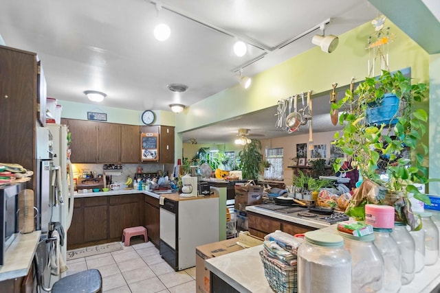2029 E Sharp Ave, Spokane, WA 99202 - kitchen featuring a peninsula, light countertops, light tile patterned floors, rail lighting, and tasteful backsplash