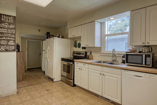 918 E Baldwin Ave, Spokane, WA 99207 - kitchen with appliances with stainless steel finishes, a sink, white cabinets, light countertops, and light flooring