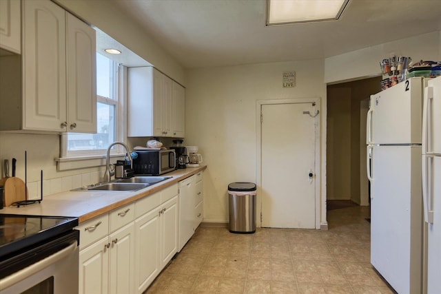 918 E Baldwin Ave, Spokane, WA 99207 - kitchen featuring appliances with stainless steel finishes, a sink, light countertops, baseboards, and white cabinetry