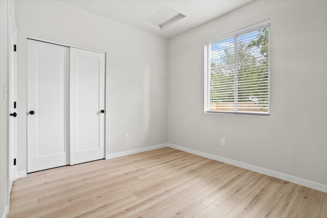 2424 N Addison St, Spokane, WA 99207 - unfurnished bedroom with light wood finished floors, baseboards, attic access, and a closet