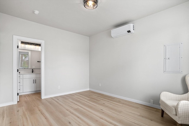 2424 N Addison St, Spokane, WA 99207 - unfurnished bedroom with a wall unit AC, electric panel, light wood-style flooring, baseboards, and a sink