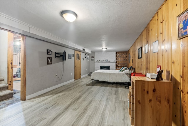 3006 W Francis Ave, Spokane, WA 99205 - bedroom featuring a fireplace, a textured ceiling, light wood finished floors, wood walls, and baseboards