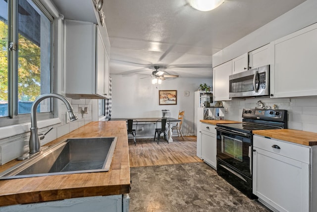 3006 W Francis Ave, Spokane, WA 99205 - kitchen with wooden counters, black electric range, stainless steel microwave, a sink, and backsplash