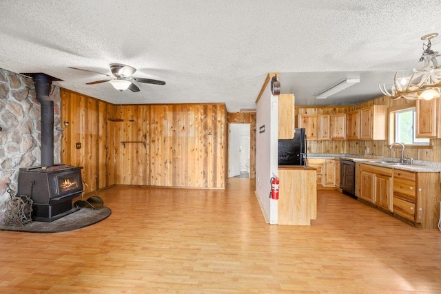 472 Snow Berry Ln, Usk, WA 99180 - kitchen featuring a textured ceiling, a wood stove, light wood-style floors, freestanding refrigerator, and a sink