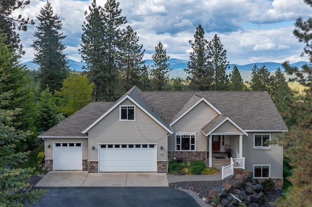 7909 N Garry Ln, Newman Lake, WA 99025 - view of front of home featuring stone siding, asphalt driveway, roof with shingles, a garage, and a mountain view