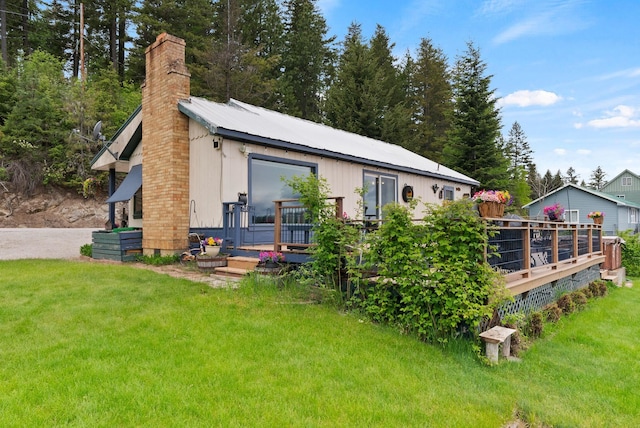46273 Larson Beach Rd, Loon Lake, WA 99148 - back of house featuring a chimney, a wooden deck, and a lawn