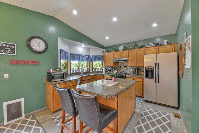 5024 E Ballard Rd, Colbert, WA 99005 - kitchen with appliances with stainless steel finishes, vaulted ceiling, a center island, brown cabinets, and dark countertops