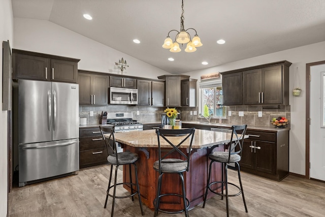 1516 E First Ct, Deer Park, WA 99006 - kitchen with stainless steel appliances, vaulted ceiling, dark brown cabinetry, a chandelier, and a kitchen breakfast bar