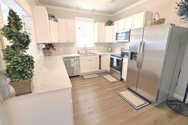 1327 N Howard St, Spokane, WA 99201 - kitchen with stainless steel appliances, a sink, light wood-style floors, white cabinets, and crown molding