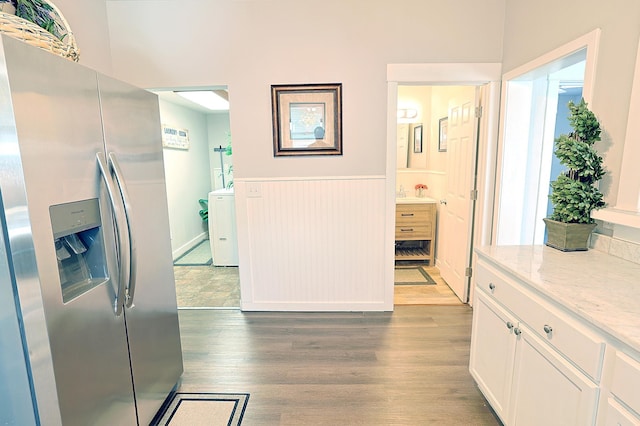 1327 N Howard St, Spokane, WA 99201 - kitchen with stainless steel fridge, wainscoting, wood finished floors, light stone countertops, and white cabinetry