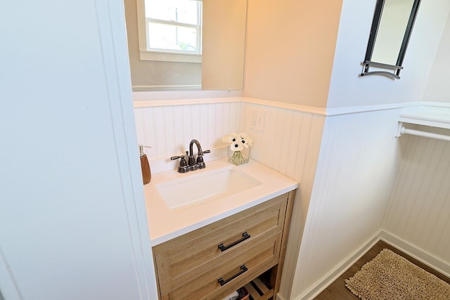 1327 N Howard St, Spokane, WA 99201 - bathroom with a wainscoted wall, vanity, wood finished floors, and a decorative wall