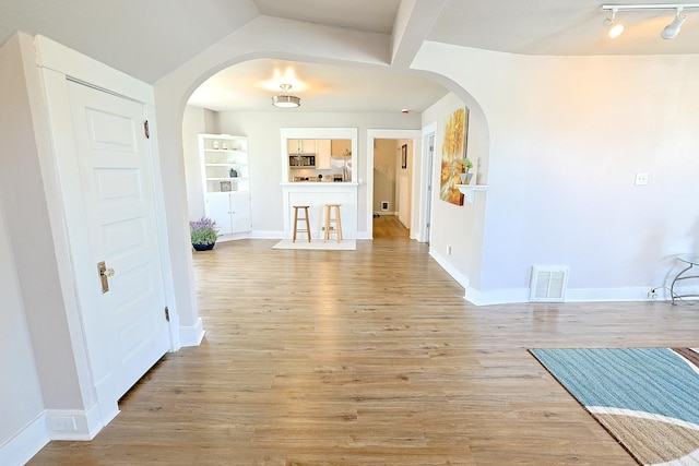 1327 N Howard St, Spokane, WA 99201 - unfurnished living room with arched walkways, baseboards, light wood finished floors, and built in features