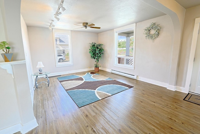 1327 N Howard St, Spokane, WA 99201 - exercise room with a baseboard radiator, ceiling fan, rail lighting, wood finished floors, and baseboards