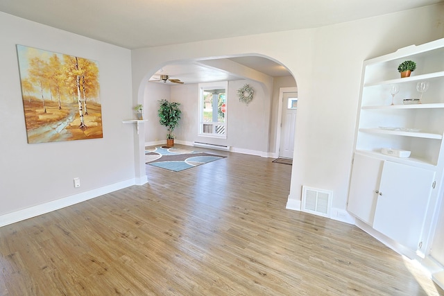 1327 N Howard St, Spokane, WA 99201 - spare room featuring arched walkways, a baseboard heating unit, light wood-style floors, baseboards, and built in shelves