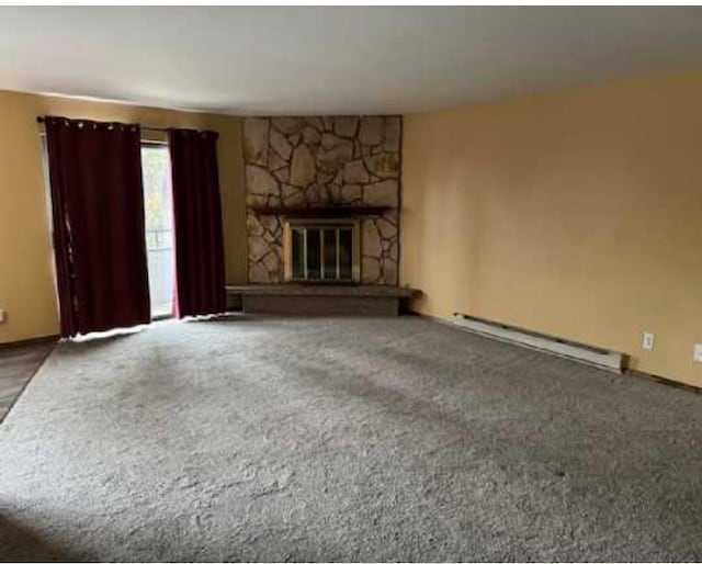 1002 W 7th Ave Unit 203, Spokane, WA 99204 - unfurnished living room featuring a baseboard radiator, carpet flooring, and a stone fireplace