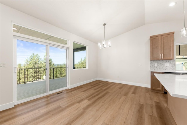 4229 W Tolliver Ct, Spokane, WA 99208 - unfurnished dining area with lofted ceiling, light wood-style flooring, a chandelier, and baseboards