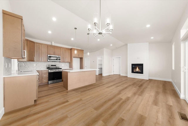 4229 W Tolliver Ct, Spokane, WA 99208 - kitchen featuring appliances with stainless steel finishes, open floor plan, vaulted ceiling, a kitchen island, and backsplash