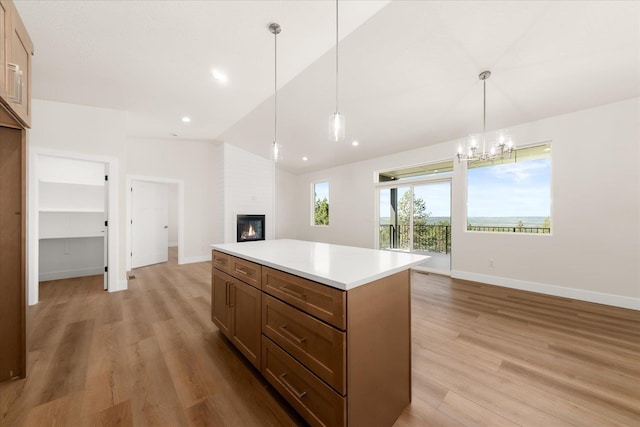 4229 W Tolliver Ct, Spokane, WA 99208 - kitchen with vaulted ceiling, open floor plan, light wood-type flooring, a large fireplace, and a kitchen island