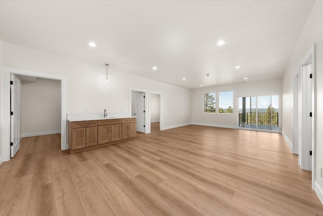 4229 W Tolliver Ct, Spokane, WA 99208 - unfurnished living room with light wood finished floors, recessed lighting, baseboards, and bar with sink