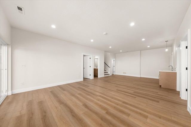 4229 W Tolliver Ct, Spokane, WA 99208 - unfurnished living room featuring light wood-style flooring, recessed lighting, baseboards, stairs, and a sink