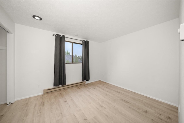 20716 E Gilbert Rd, Otis Orchards, WA 99027 - unfurnished bedroom with a baseboard heating unit, light wood finished floors, baseboards, and a textured ceiling