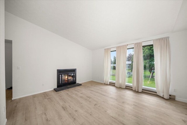 20716 E Gilbert Rd, Otis Orchards, WA 99027 - unfurnished living room featuring light wood-style flooring, vaulted ceiling, a glass covered fireplace, and baseboards